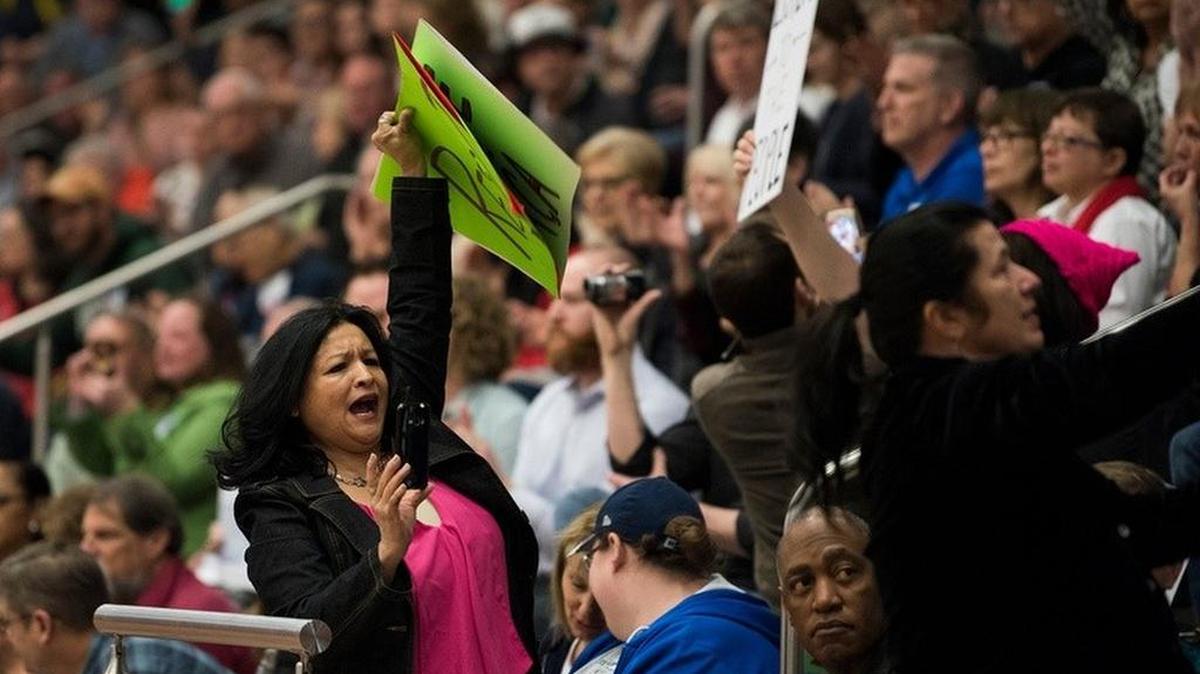 Attendees hold up signs in the bleachers at a town hall meeting in Flower Mound held by U.S. Rep. Michael Burgess on Saturday.