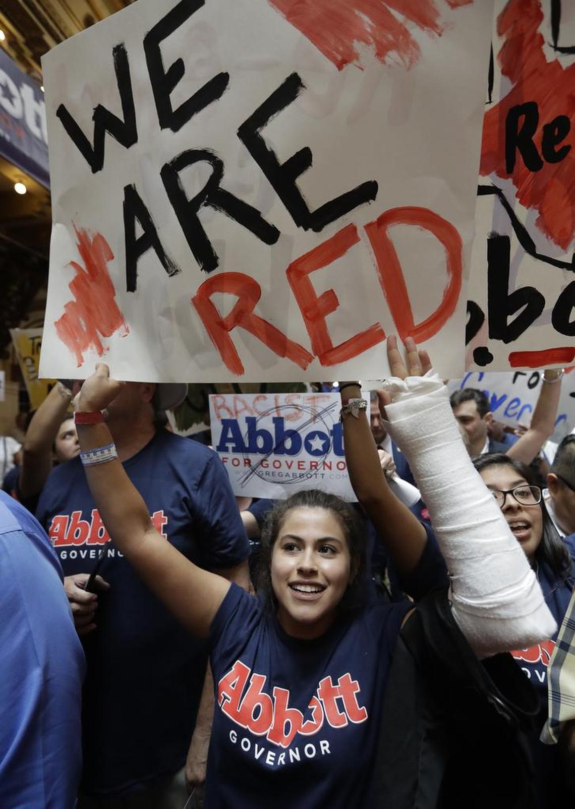 A supporter of Texas Gov. Greg Abbott uses a sign to block protesters prior to an event where Abbott announced his bid for re-election.