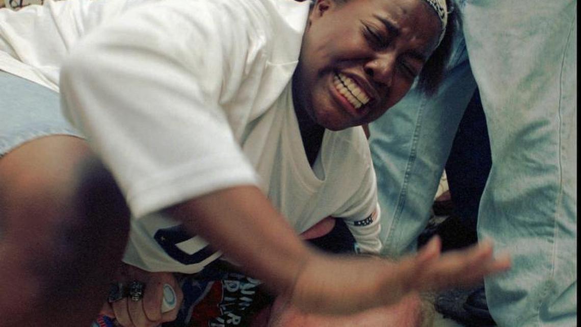 In this June 22, 1996, file photo, Keshia Thomas, then 18, of Ann Arbor, Mich. uses her body to shield a man from a crowd of anti-Klan demonstrators who were beating him with sticks after he was spotted wearing a Confederate flag on his jacket during a Ku Klux Klan rally in Ann Arbor. "Just because you beat somebody doesn't mean you're going to change his mind," Thomas said.