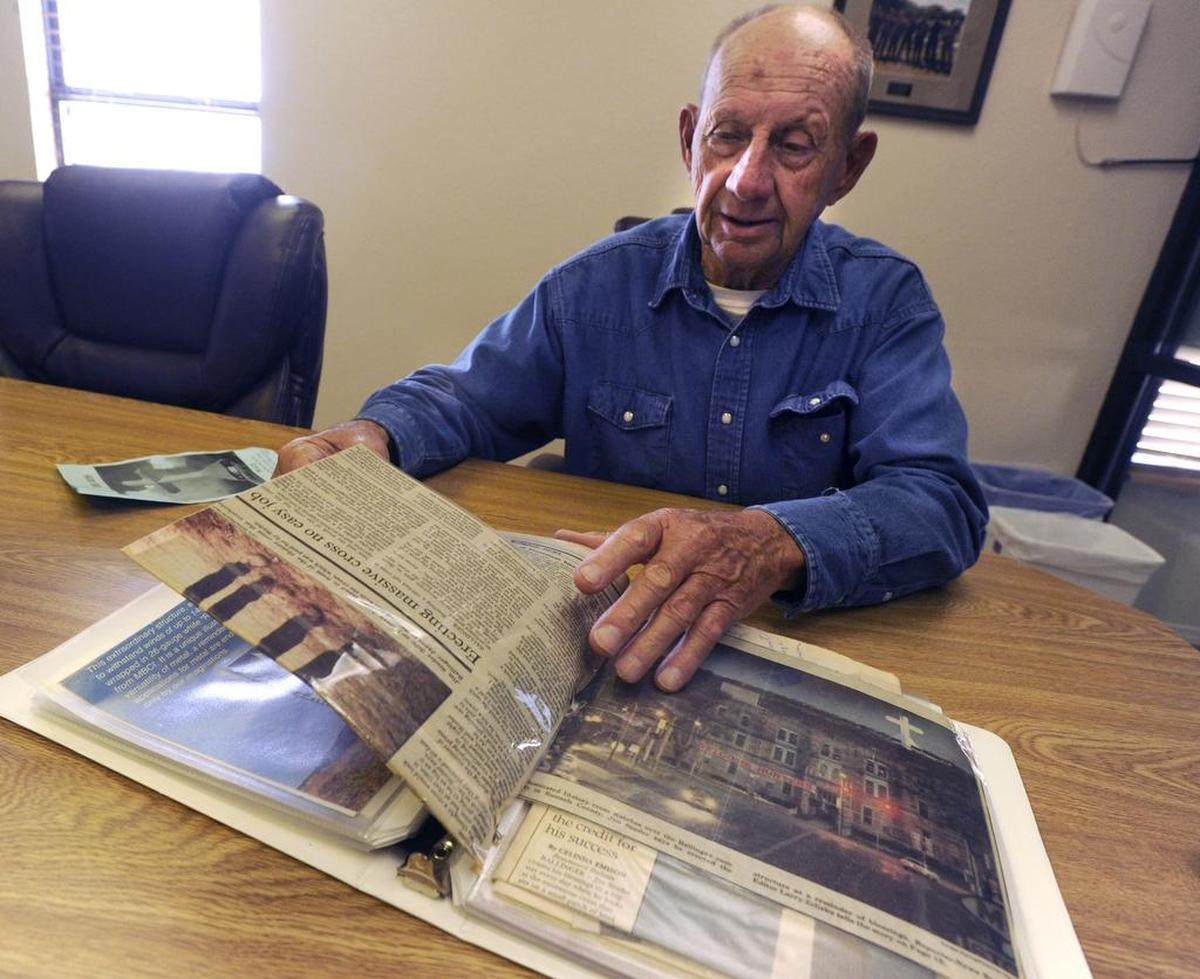 Jim Studer flips through a scrapbook of newspaper articles and photographs in Ballinger. The book depicts the construction of the 99-foot steel cross he commissioned on his property a mile and a half south of town.