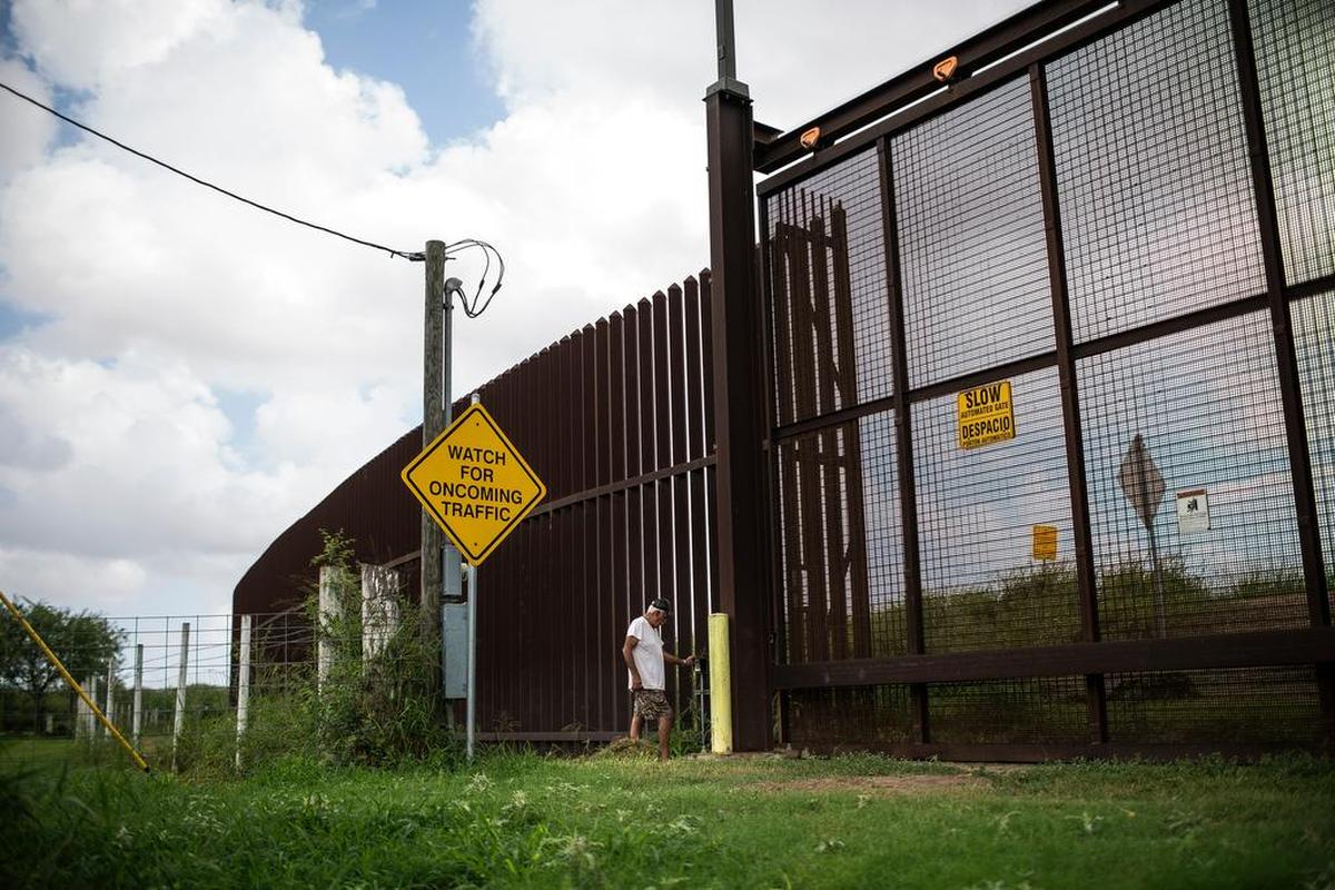 Juan Cavazos enters the code for the gate at the border wall that cuts through his property on Oklahoma Avenue in Brownsville.