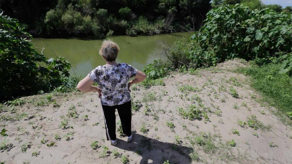 Pamela Taylor, whose home is on the south side of the border fence, stands near the Rio Grande in Brownsville. The last time U.S. officials built a barrier along the border with Mexico, they left an opening at the small road leading south to Taylor’s home.