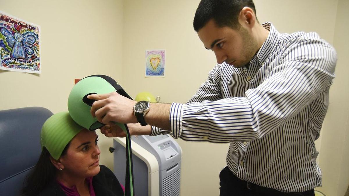 Adrianne Frost, left, is fitted with a Dignicap at the Cancer Therapy and Research Center in San Antonio in February. The device allows women undergoing chemotherapy for breast cancer to keep their hair.