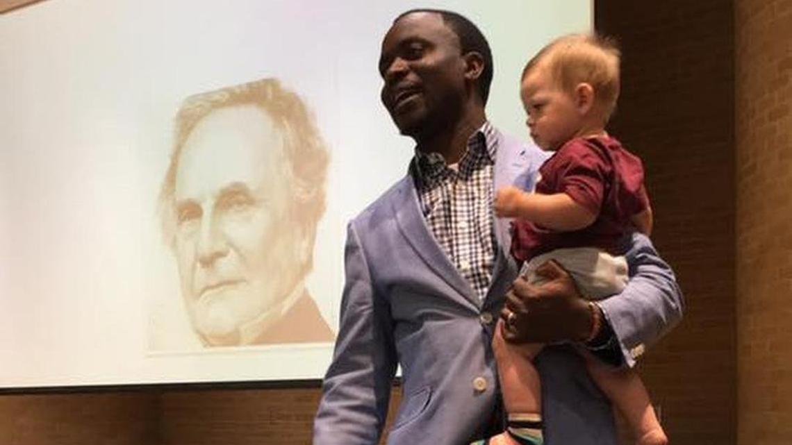 Dr. Henry Musoma holds Ashton Robinson’s son, Emmett, during his lecture at Texas A&M on Sept. 7.