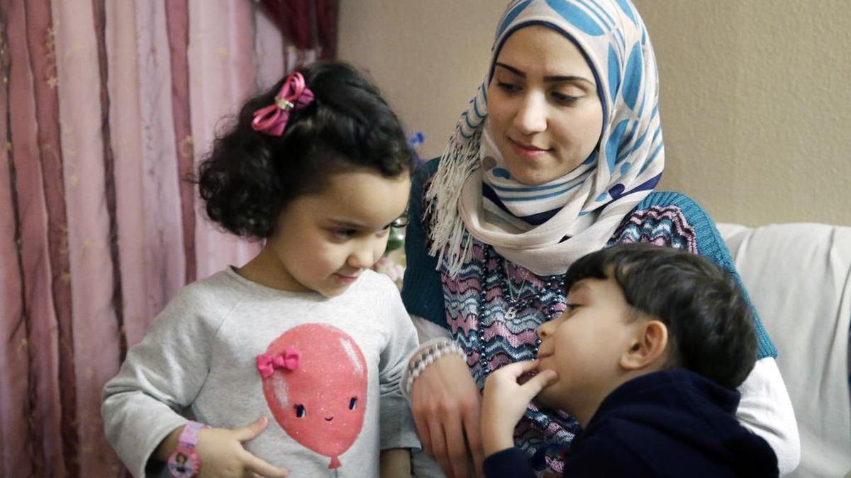 In this photo from Nov. 29, Syrian refugee Maryam al Jaddou, center, looks on as her children twins Maria, left, and Hasan, sit with her at their apartment in Dallas. More than 800 Syrians have resettled in Texas this fiscal year, according to state and federal figures.