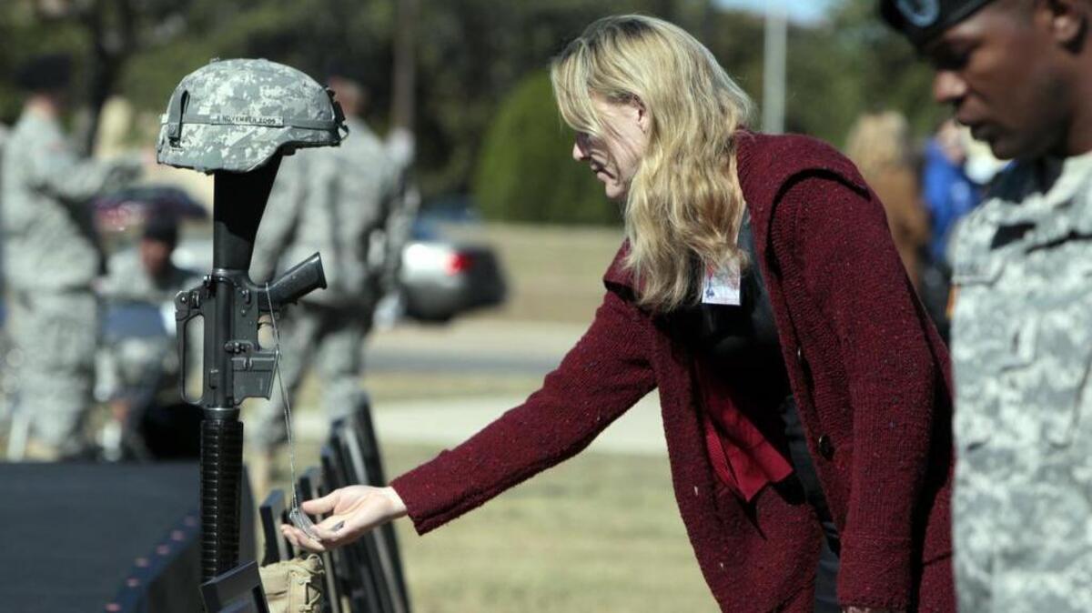 Kerry Cahill, the daughter of Chief Warrant Officer Two (Ret.) Michael Cahill, touches the dog tags representing the 13 killed, including her father, in the Fort Hood shooting massacre in 2009.