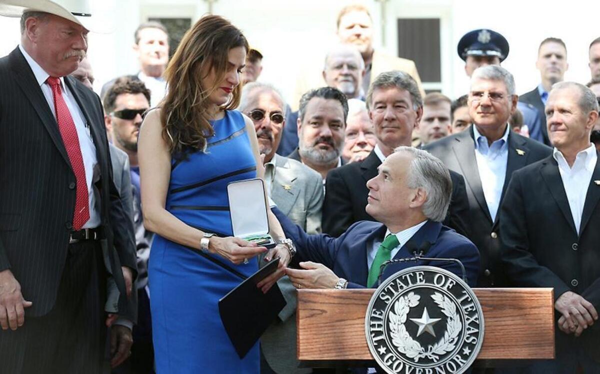 
Taya Kyle of Midlothian, the widow of “American sniper” Chris Kyle, accepts the Legislative Medal of Honor from Texas Gov. Greg Abbott Wednesday as she stands with veterans she asked to join her at the podium during a ceremony on the front lawn of the Governor’s Mansion in Austin. 
