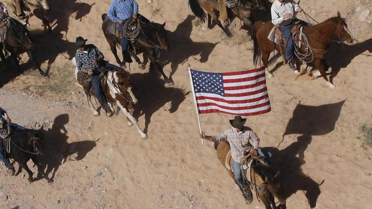 FILE: In this April 12, 2014, file photo, the Bundy family and their supporters fly the American flag as their cattle is released by the Bureau of Land Management back onto public land outside of Bunkerville, Nev. The federal Bureau of Land Management says six cattle died in the roundup of animals it says rancher Cliven Bundy allowed to graze illegally on public land outside his southern Nevada property. A Texas land dispute has Gov. Greg Abbott, decrying the same federal agency currently embroiled in an armed standoff in Nevada. (AP Photo/Las Vegas Review-Journal, Jason Bean, File) LOCAL TV OUT; LOCAL INTERNET OUT; LAS VEGAS SUN OUT