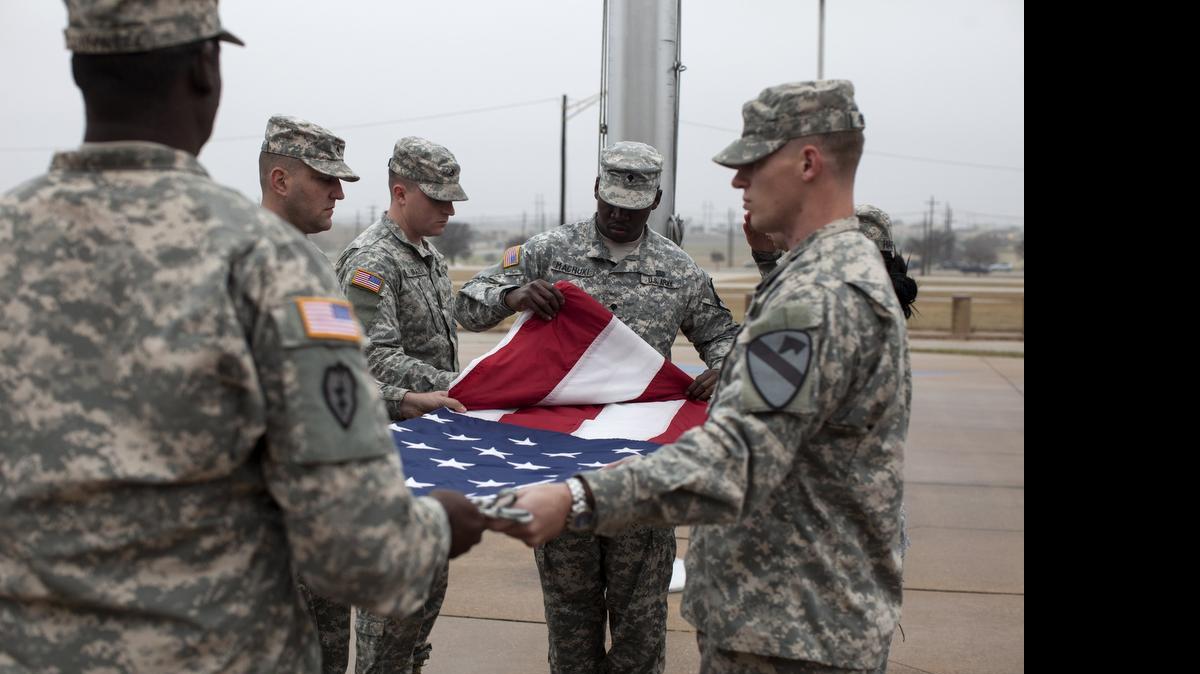 
Soldiers fold a lowered flag at Fort Hood, Texas, the largest army base in the United States, Dec. 30, 2014. Though that day marked the official end of the war in Afghanistan, the date means little to many of the families on this sprawling installation where the wounds of wars that began after 9/11 are still ever present. The base now faces troop cuts. (Ilana Panich-Linsman/The New York Times)
