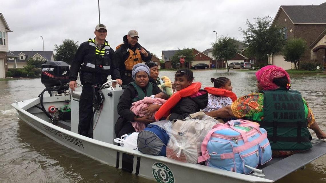 Denton County game warden Josh Bulger and Fort Bend County Sheriff’s deputy Casey Schmidt ferry a family to safety Tuesday after their neighborhood in Richmond flooded due to rains associated with Tropical Storm Harvey.