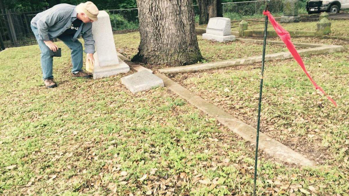 
Bill Warren spruces up the Wright family marker Friday. A flag marks where Jim Wright will be buried.
