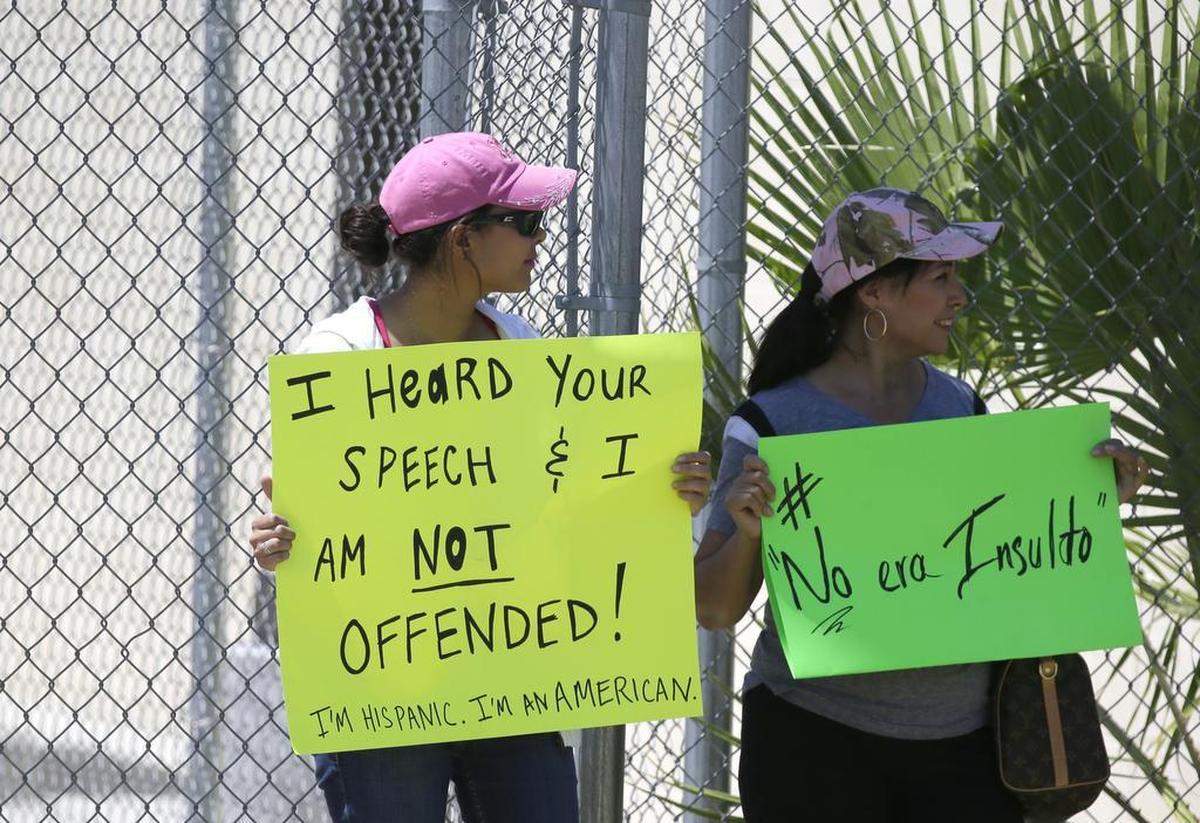 Two women hold signs while waiting for Republican presidential hopeful Donald Trump in Laredo.