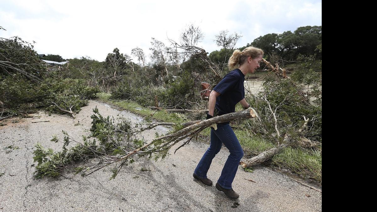 
Andrea Jones helps remove a downed tree on River Road, Monday, May 25, 2015, in Wimberley, Texas. Around a dozen people were reported missing in flash flooding from a line of storms that stretched from the Gulf of Mexico to the Great Lakes. 

