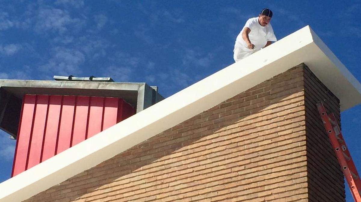 Worker Juan Ortiz puts the last touches on the restored red chimney and modern roofline of what is now the 6421 Camp Bowie building.