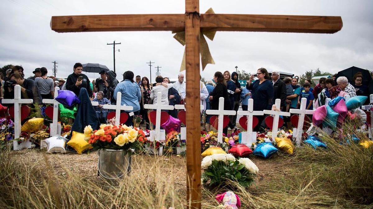 Dozens of people stand in the rain to pray and sing at the memorial crosses near the First Baptist Church of Sutherland Springs, Texas, one week after 26 people were killed there.