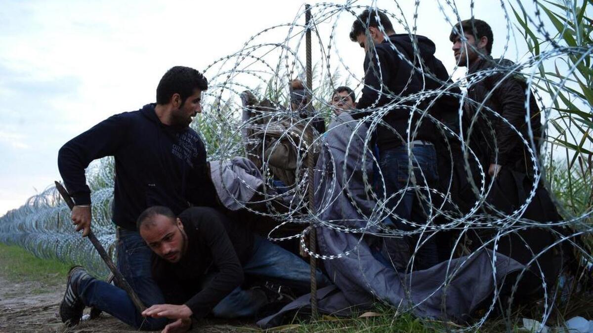 
Syrian refugees cross into Hungary underneath the border fence on the Hungarian-Serbian border near Roszke, Hungary. 
