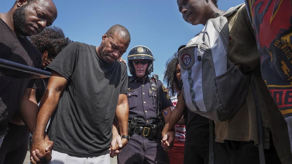 Sgt. Paul Hinton, center, prays with a group of Black Lives Matter marchers in Dallas on Sunday.