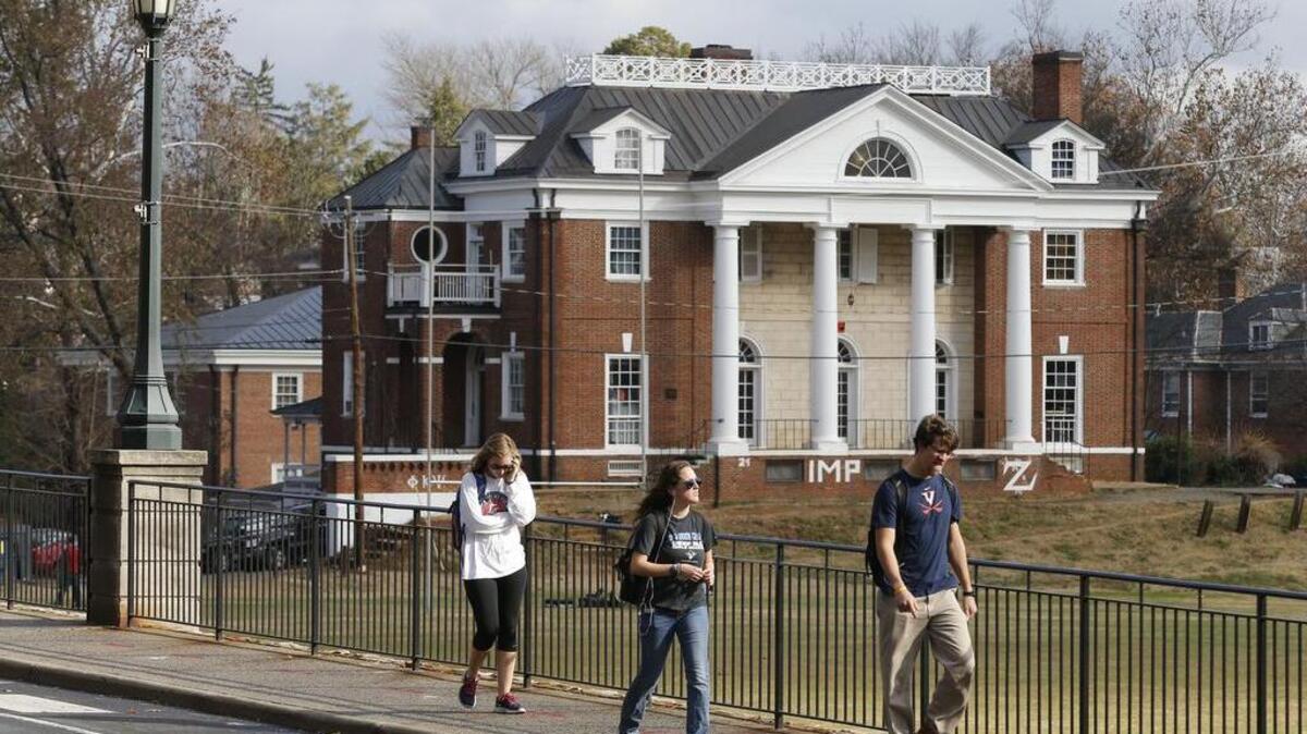 
University of Virginia students walk to campus past the Phi Kappa Psi fraternity house at the University of Virginia in Charlottesville, Va. Rolling Stone’s account of a young woman who says she was gang-raped at a fraternity party has been debunked.
