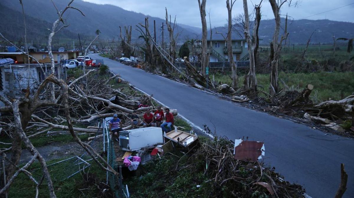 Neighbors sit on a couch outside their destroyed homes, wrecked by Hurricane Maria, in Puerto Rico, Tuesday.