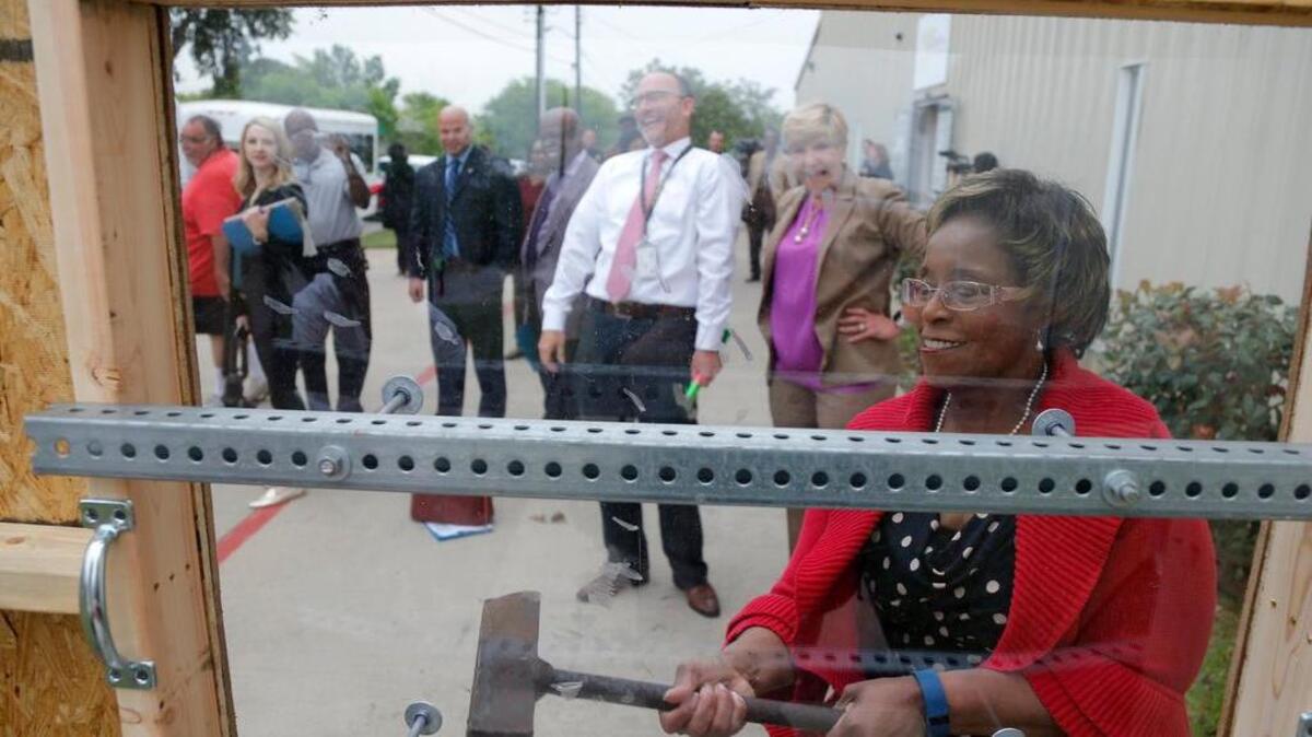Councilmember Gyna Bivens attempts to break a shatter-resistant window with a sledge hammer after Mayor Betsy Price and members of the City Council tour Stop Six on Tuesday to talk about improvements.