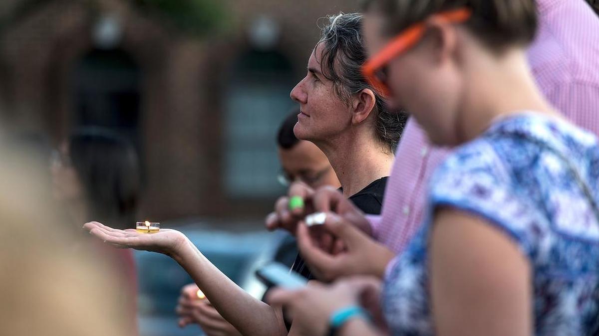 Cristina Graber Neufeld holds a candle as she listens to people give first-hand accounts of yesterday's protests in Charlottesville, Va., during a candlelight vigil on Sunday, Aug. 13, 2017, in Harrisonburg, Va. The vigil was held for the victims of the violence in Charlottesville on Saturday.