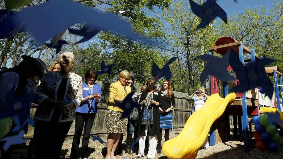 Paper pin wheels fall during the Shades of Blue program as Fort Worth Mayor Betsy Price, center, and board members of the Parenting Center of Fort Worth raise awareness for Child Abuse Prevention Month Monday March 28, 2016.