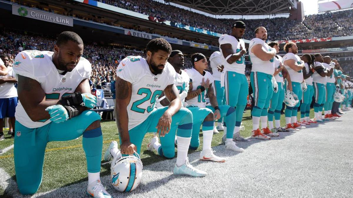 Some Miami Dolphins players kneel during the singing of the national anthem before an NFL football game.