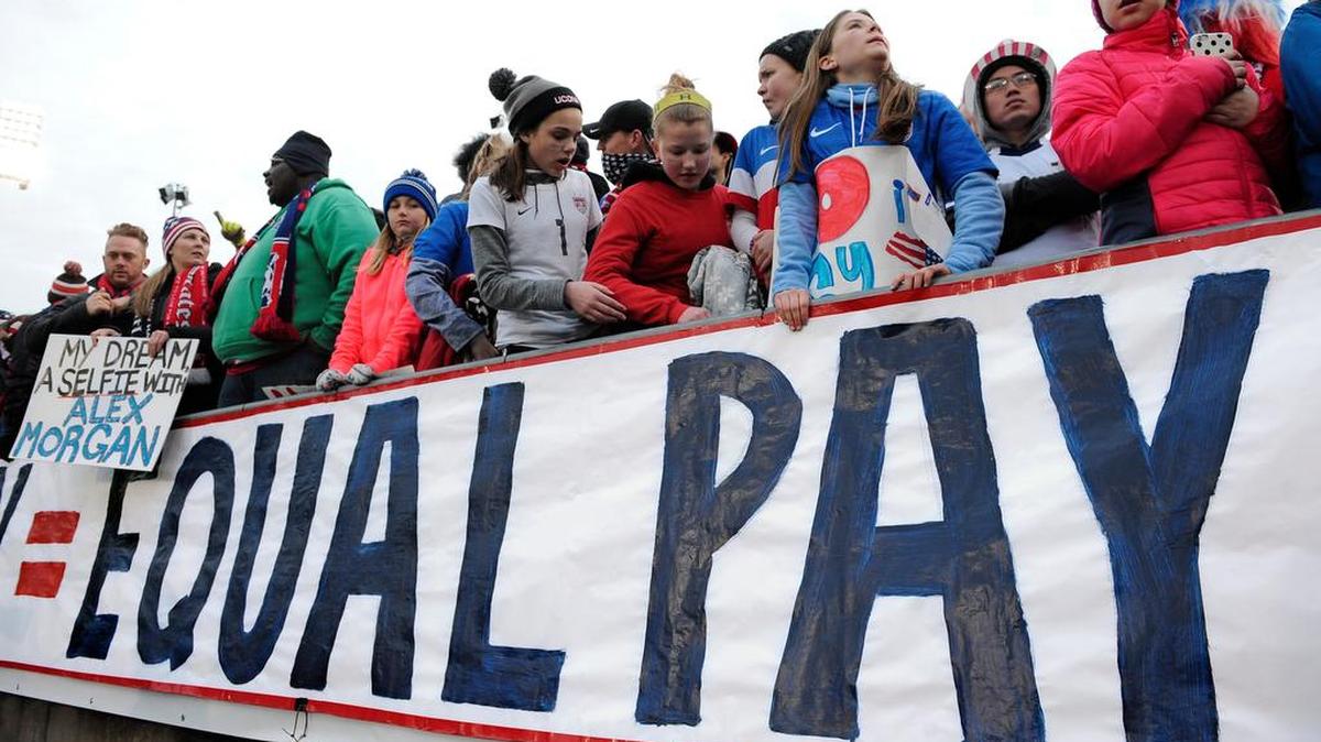 Fans stand behind a equal pay sign during an friendly U.S. women’s soccer match against Colombia last year.