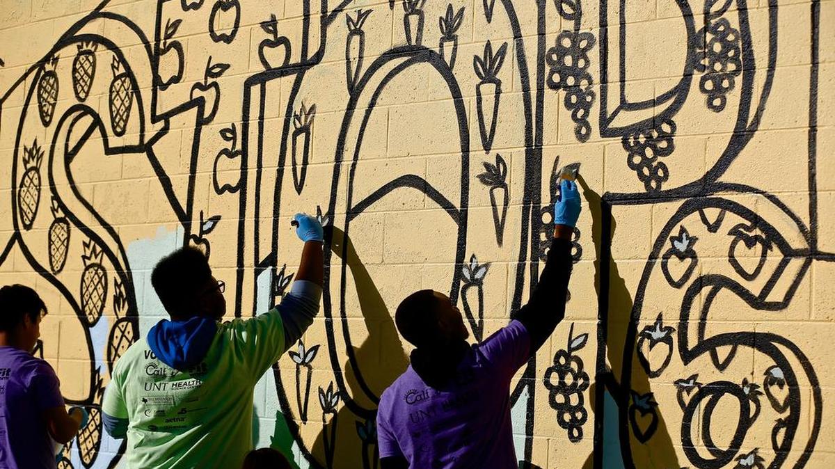 Art students from Dunbar High School paint in a mural that they designed and outlined in the Stop Six area.