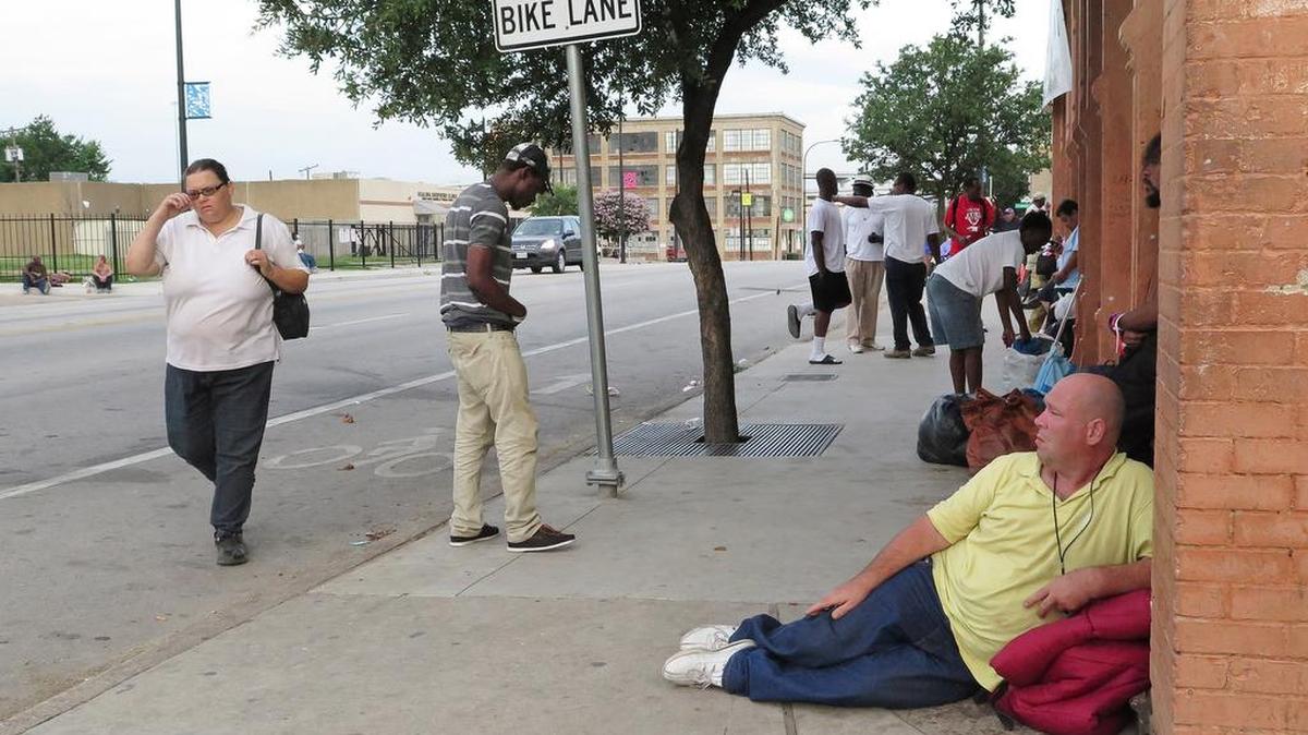 People pass time during warm weather outside the DRC’s day shelter on East Lancaster Avenue.