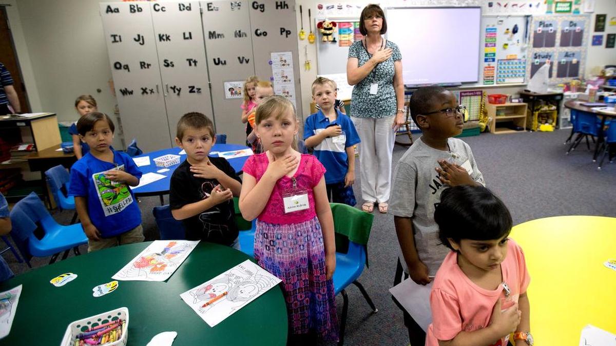 
Kindergarten teacher Sherry Uribe leads her students in the pledge of allegiance to start off the first day of school at Shady Brook Elementary School in Bedford on Aug. 24. 
