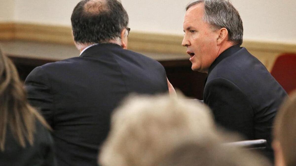 
Texas Attorney General Ken Paxton, right, visits with his attorney during his arraignment on securities fraud charges on Aug. 27. 
