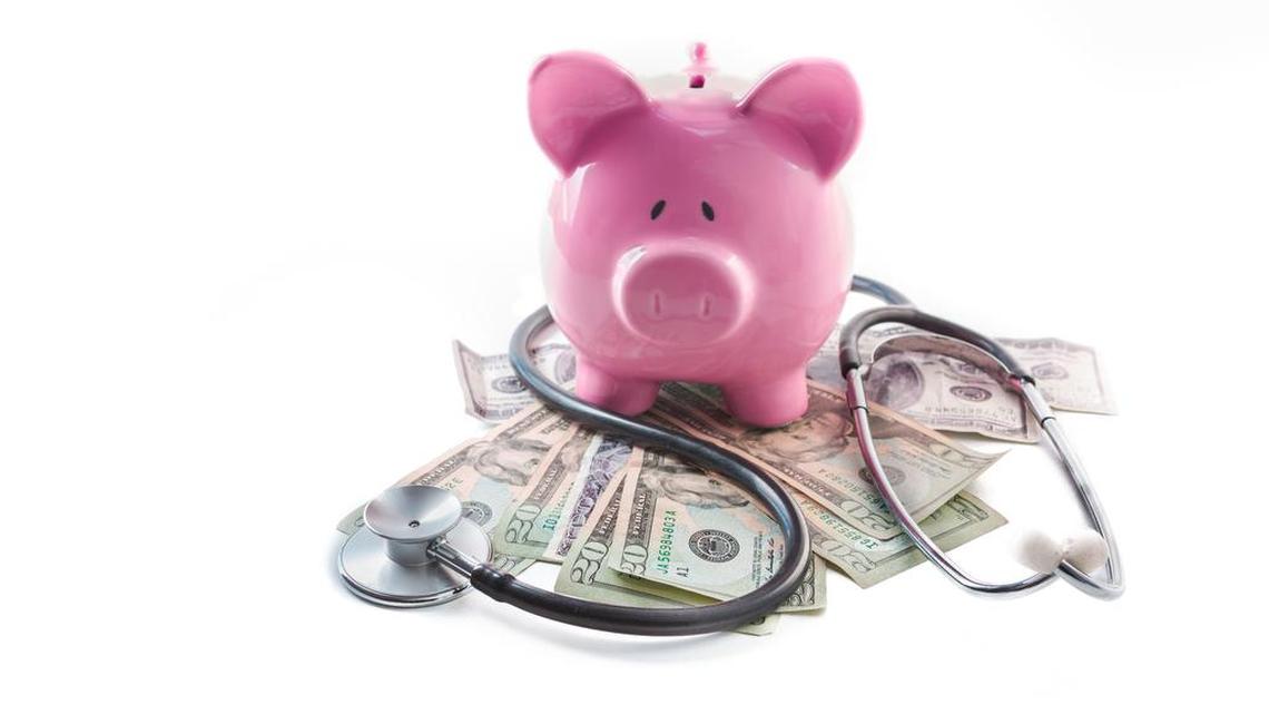 Piggy bank and stethoscope resting on pile of dollars.