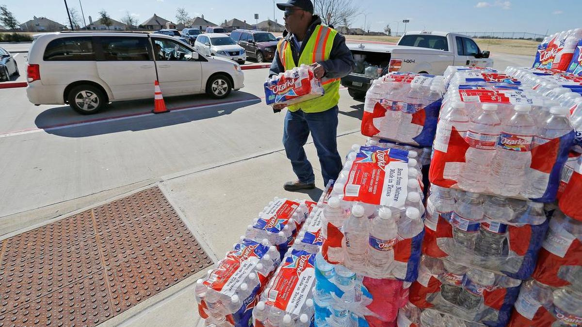 Carl Sherman of the Fort Worth Water Department, carries a case of bottled water to a car Thursday at Wilson Middle School on Sendera Boulevard.