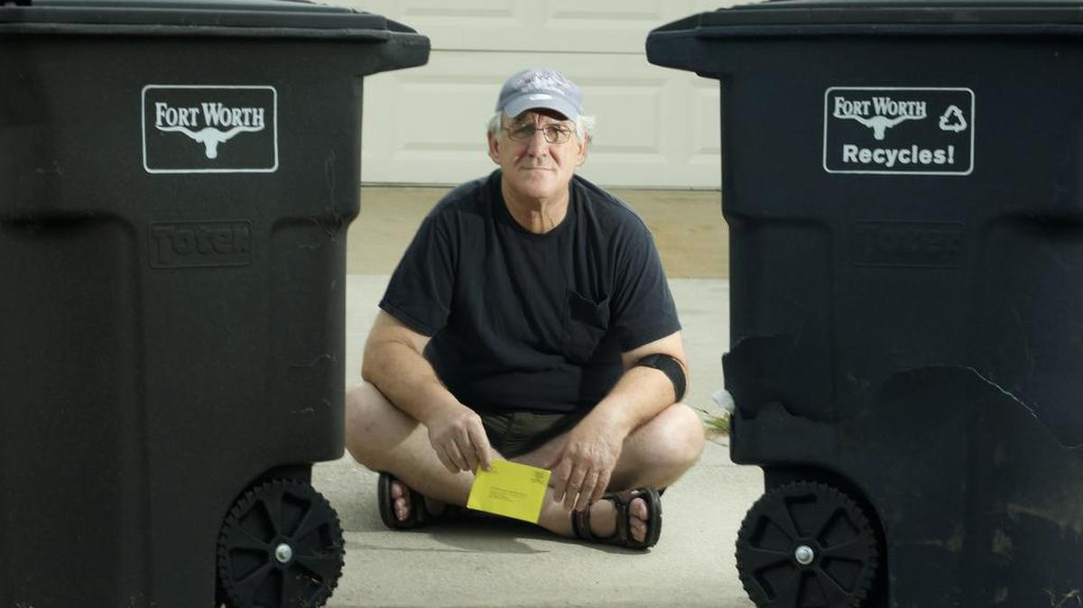 Robert Damora holds a notice about a warrant for his arrest after failing to properly discard trash and recycling at his home in north Fort Worth.