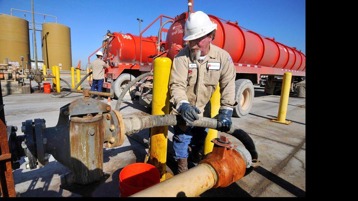 
Workers at a disposal well connect hoses to inject drillng wastewater deep underground. 
