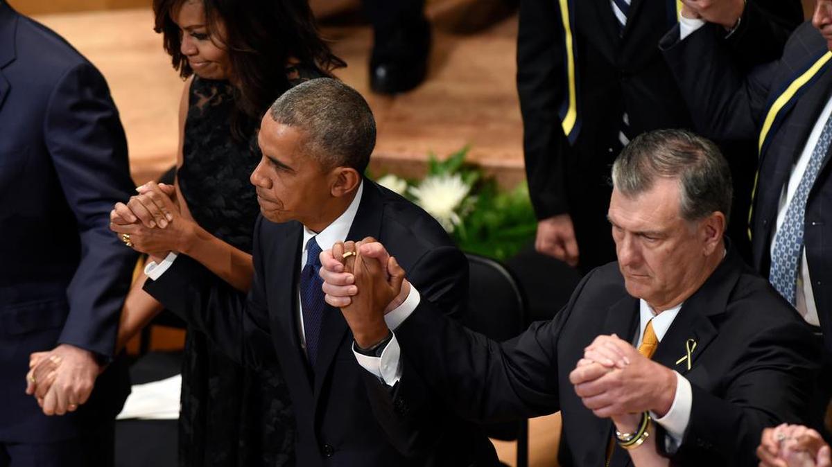 President Barack Obama holds hands with Dallas Mayor Mike Rawlings, right, and first lady Michelle Obama during an interfaith memorial service for the fallen police officers and members of the Dallas community Tuesday at the Morton H. Meyerson Symphony Center in Dallas.