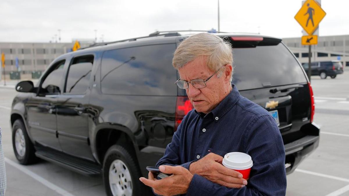 Uber driver Marcos N. Suarez checks his phone as he receives notice that he has a customer at DFW International Airport.