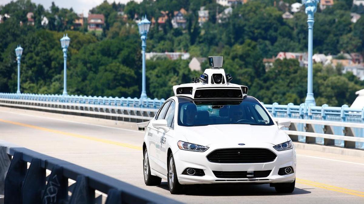 Uber employees test a self-driving Ford Fusion hybrid car in Pittsburgh last year.