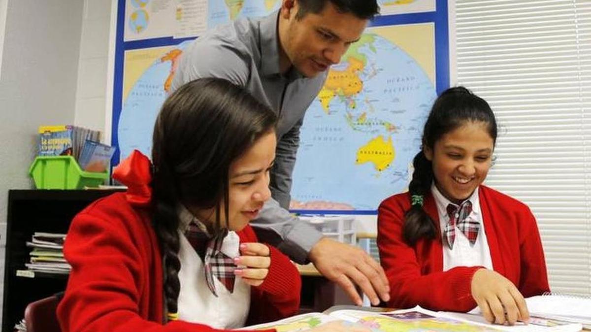 Social studies teacher Jairo Rios, who conducts his class entirely in Spanish, helps Velia Olvera and Neli Alvarez at the Fort Worth school district’s World Languages Institute on Magnolia Avenue.