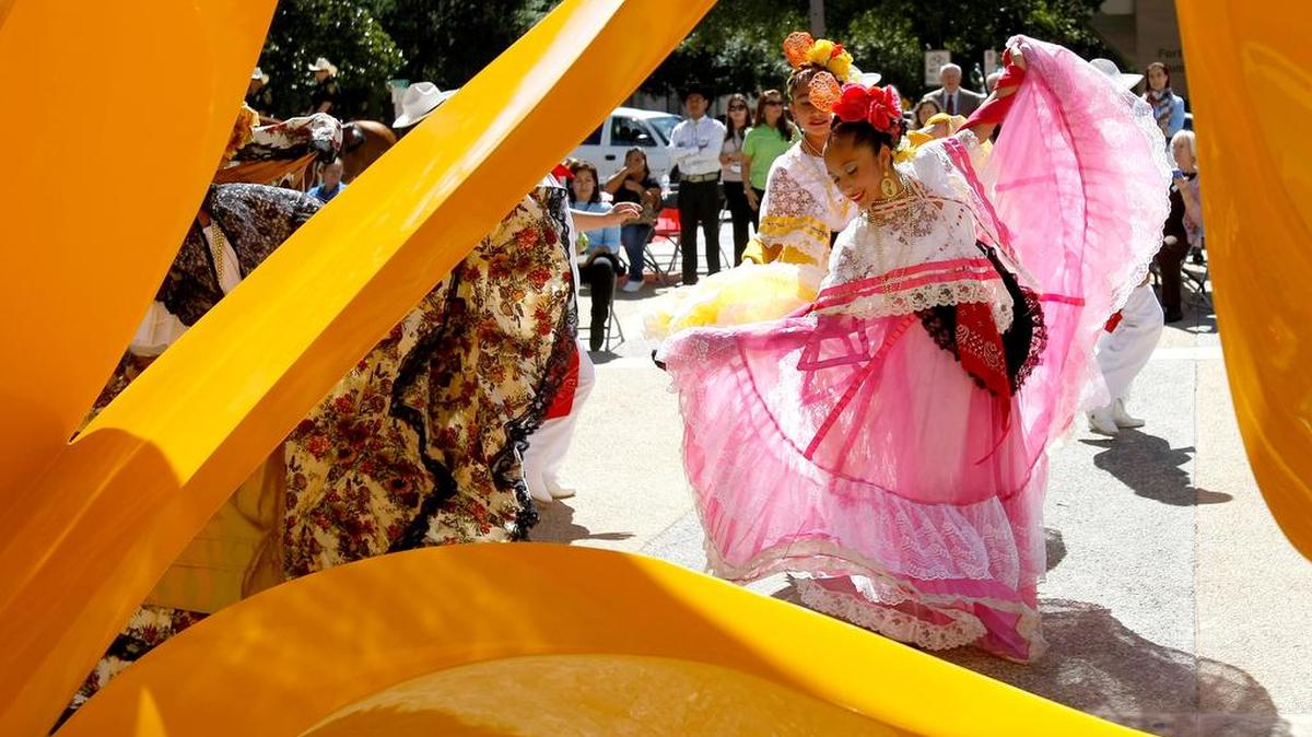 Mexico Lindo Ballet Folklorico dancers are framed by the sculpture Tabachin Ribbon as they perform during the 13th Annual Hispanic Heritage City Employee Celebration in downtown Fort Worth on Wednesday, October 15, 2014.