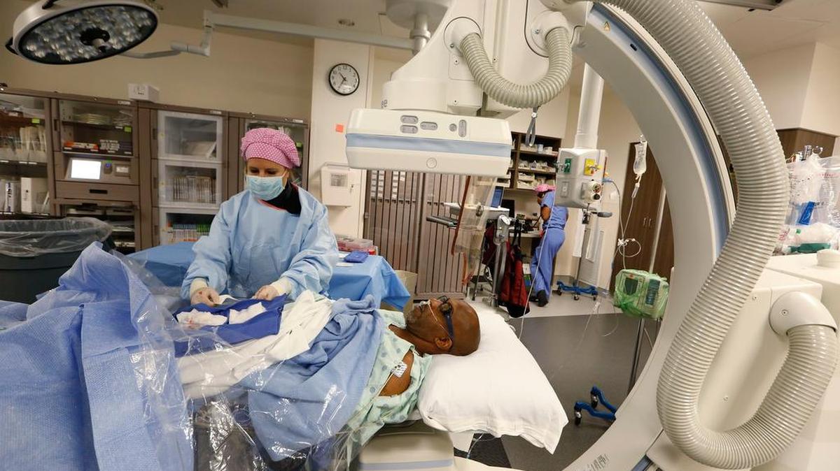 Scrub nurse Lisa Elia, RN, puts a bandage over the wound that has been sealed with a special plug after a heart catheterization procedure at the new Heart and Vascular Invasive Care Center, at JPS Health Network Patient Care Pavilion in 2015.