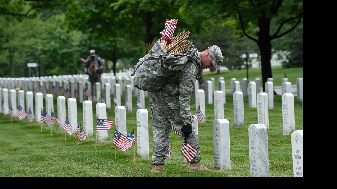 
Placing flags in front of headstones at Arlington National Cemetery Thursday. 
