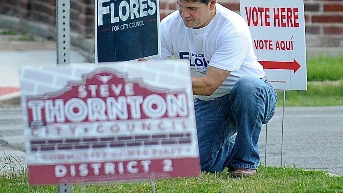 Carlos Flores places a campaign sign at Ruffino Mendoza Elementary School in Fort Worth on June 10.