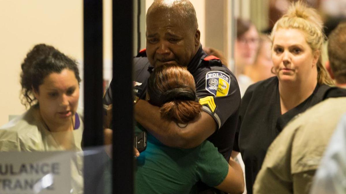 A DART police officer is comforted at Baylor University Hospital on Thursday in Dallas.