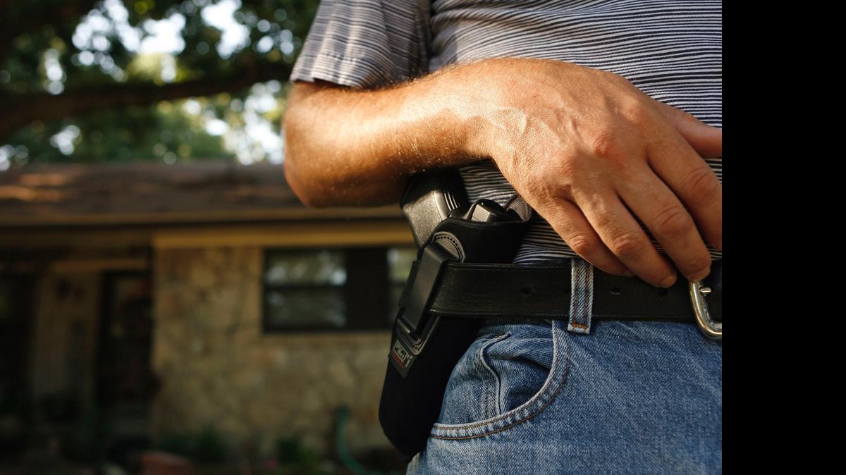 
A gun owner shows his 40 caliber Glock 23 semi-automatic pistol holstered on his hip. 

