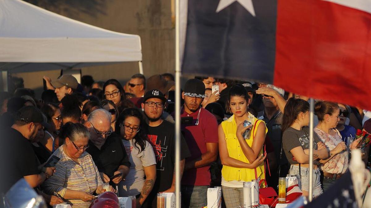 People visit a makeshift memorial at the scene of a mass shooting at a shopping complex Tuesday in El Paso, Texas.