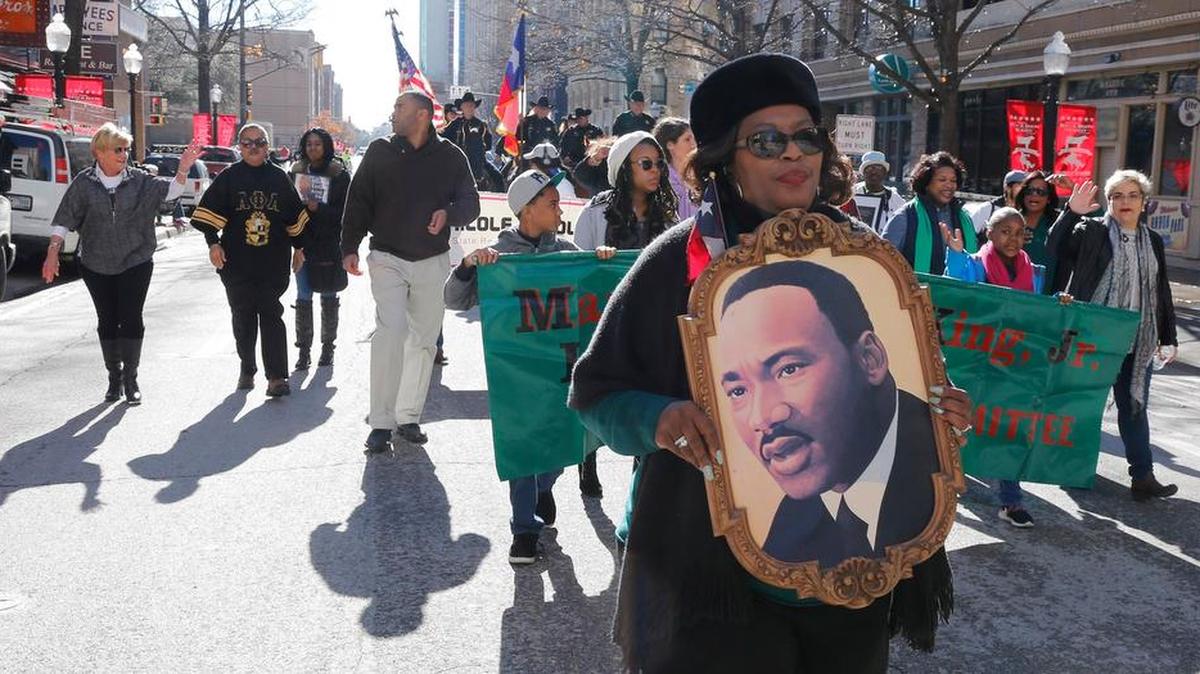 Patricia Bell carries a portrait of Dr. King at the Martin Luther King Day Parade in downtown Fort Worth followed by a Battle of the Bands in Sundance Square, Monday.