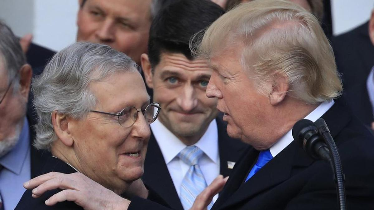 President Donald Trump congratulates Senate Majority Leader Mitch McConnell while House Speaker Paul Ryan watches after final passage of tax overhaul legislation by Congress at the White House in Washington, Wednesday, Dec. 20, 2017.