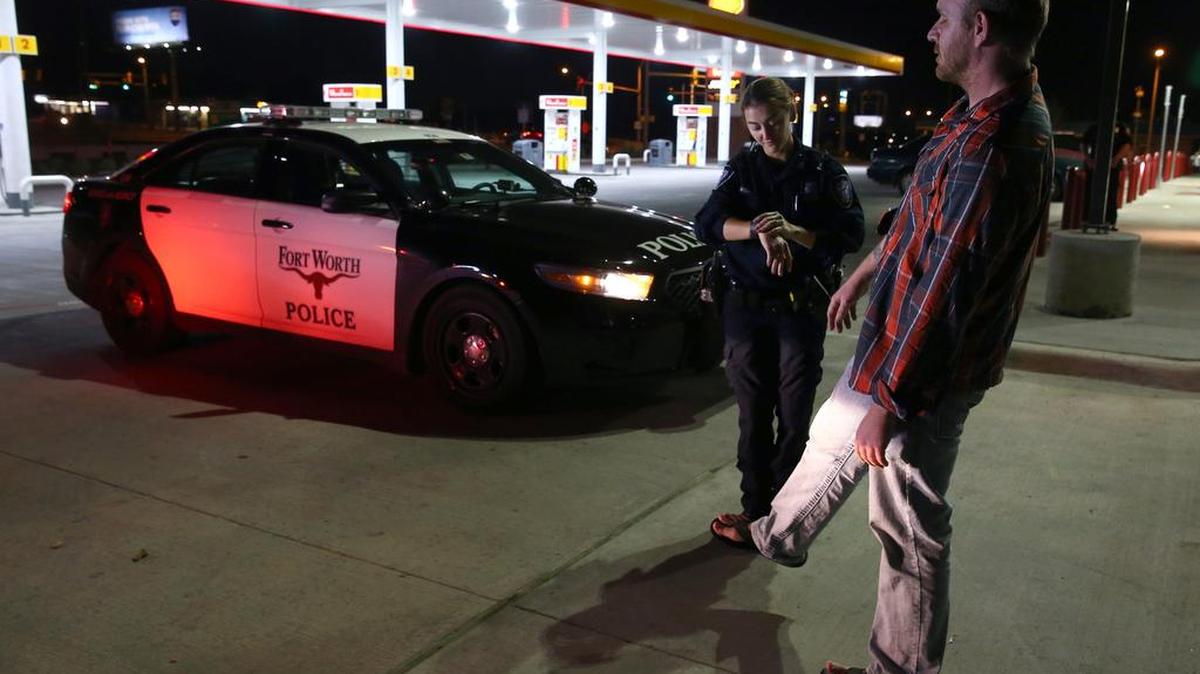 A police officer administers a field sobriety test to a driver who was pulled over for suspicion of driving while intoxicated.